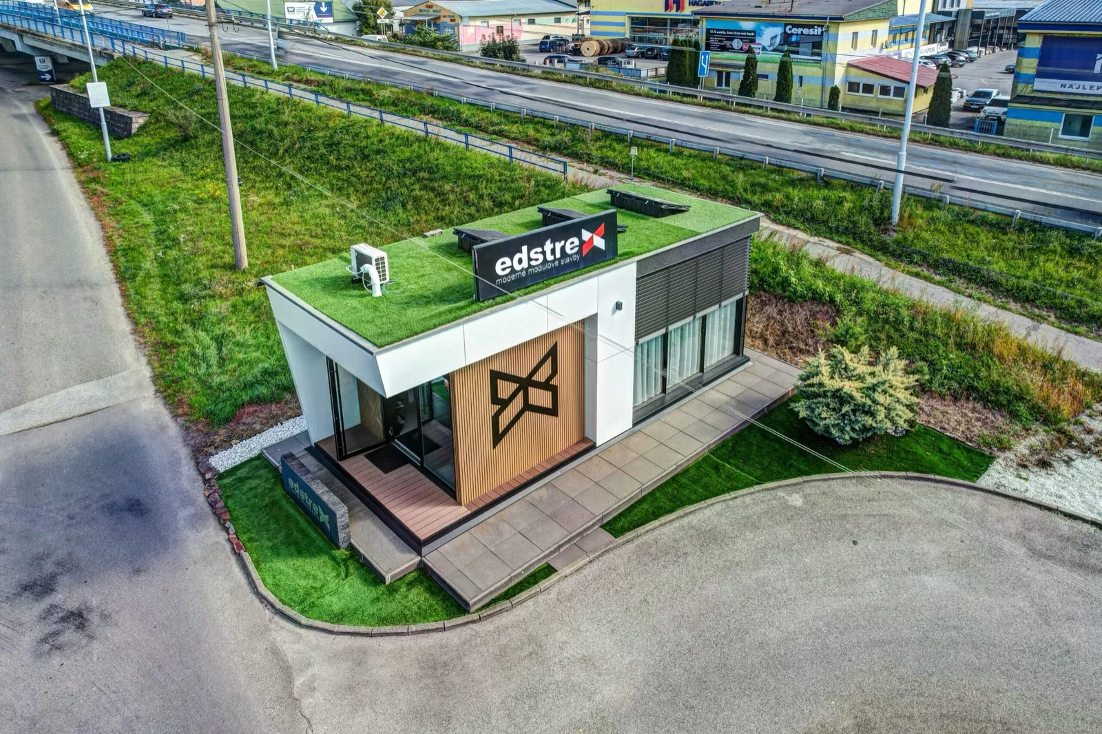 Aerial view of the Edstrex showroom, a modular building with a green roof and timber-clad facade beside a main road